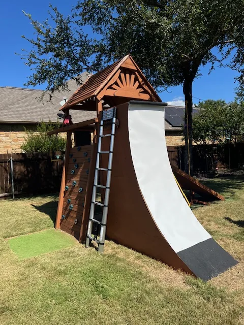 Front view of a customer-built white warped wall integrated into a backyard playset